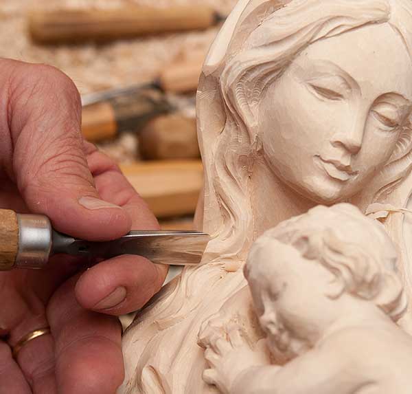 The woodcarver finishes the rough-hewed figure, giving his personal touch